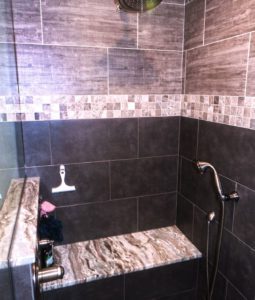walk-in shower with bench seating and glass doors. Also includes a hand held spray plus a large rain head shower fixture.