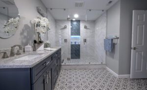 Large walk-in shower, double vanity, patterned floor tile, marble shower wall tile with decorative mosaic.