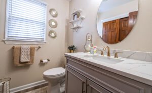 Powder Room with gray cabinets, natural stone countertop, neutral color scheme.